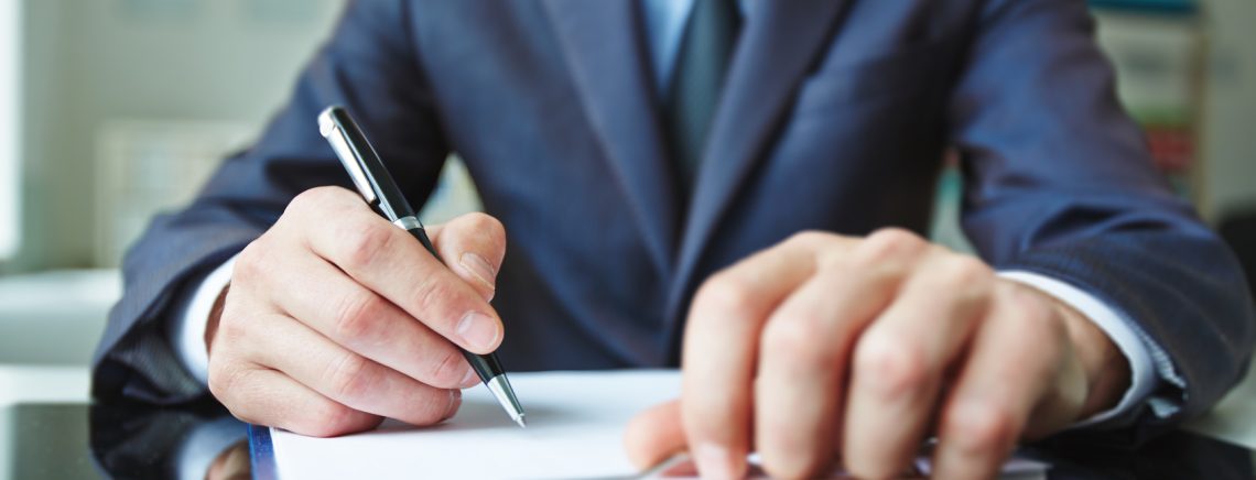 Close-up of male hand signing a document